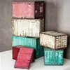 A collection of storage boxes designed to look like industrial shipping containers, stacked and arranged on a white surface against a gray wall. Produktbild-Vorschau