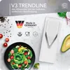 A white vegetable slicer is shown next to a salad and ingredients on a textured gray and white surface. Podgląd zdjęcia produktu
