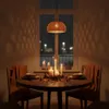 A dining table set for a cozy evening with candles and warm lighting, with a window showing a rainy night scene. Produktbild-Vorschau