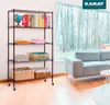 A black metal shelving unit filled with books, baskets, and decorative items, placed in a living room setting next to a sofa and a large window. Náhled obrázku produktu