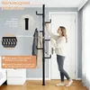 A woman is shown assembling a tall, black, telescopic coat rack in a room with a door and a nightstand. Produktbild-Vorschau