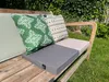 A heated outdoor seat cushion on a wooden bench in a garden setting. Náhled obrázku produktu