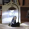 A decorative lamp ornament of a character from Japanese animation, placed on a wooden surface in front of a white photo frame. Produktbild-Vorschau