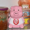 A pink piggy bank with a white bib labeled 'Diet Piggy' sits on a shelf in a refrigerator next to jars and cans of food. Podgląd zdjęcia produktu
