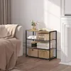 A three-tier shelving unit with various items on display, next to a sofa in a room. Produktbild-Vorschau