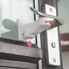 A close-up shot of a white childproof lock attached to a door handle and frame. Produktbild-Vorschau