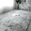 A fluffy gray rug with an open book on it, next to a polka-dot cushion and a plant. Náhled obrázku produktu