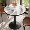 A round marble-patterned table with two cups of coffee and a vase of flowers, placed near a window with greenery outside. Two chairs are partially visible. Anteprima dell’immagine prodotto