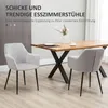 Two light gray dining chairs are placed around a wooden dining table with black legs. A vase with flowers and a cup are on the table. Voir les images du produit