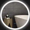 A modern bathroom scene featuring a round illuminated mirror reflecting a bathtub and a wooden side table with toiletries. Produktbild-Vorschau