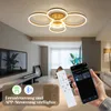 A modern living room with a ceiling light, TV, and furniture. A hand holds a smartphone and a remote control, indicating smart home features. Náhled obrázku produktu