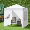 A white gazebo set up on a green lawn with a chair and table inside. Náhled obrázku produktu