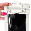 A hand with pink fingernails is shown closing a white waterproof phone case with a black phone inside. Produktbild-Vorschau