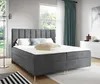 A bedroom scene featuring a large gray upholstered bed with gold legs, set against a window with green curtains.