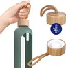 A hand holding a water bottle, with close-ups of the bottle cap and a bamboo leaf icon. Voir les images du produit