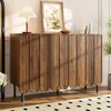 A modern wooden sideboard with decorative wavy doors, placed in a well-lit room with a lamp, artwork, and plants. Voir les images du produit