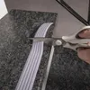 A hand is using scissors to cut a strip of anti-slip tape on a granite surface. Náhľad obrázku produktu