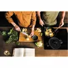 Two people are preparing food in a kitchen, with a cookbook open on the counter. Podgląd zdjęcia produktu