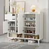 A white shoe cabinet with multiple shelves and doors, filled with various shoes. A lamp and decorative items are on top. Anteprima dell’immagine prodotto