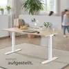 An office desk with a partition, plants, and office supplies, with two children blurred in the background. Náhled obrázku produktu