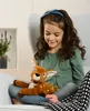 A young girl sitting in a chair, holding a stuffed deer. Produktbild-Vorschau
