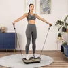 A woman is using a vibration plate machine with resistance bands in a home setting. Náhled obrázku produktu