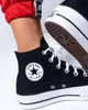 A close-up shot of a person wearing black Converse Chuck Taylor All Star Lift Hi sneakers. Voir les images du produit