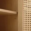 A close-up view of a wooden cabinet with a cane-like pattern on the side and a shelf. Voir les images du produit