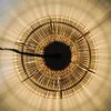 A close-up view of a woven light fixture, showing the intricate pattern of the material and the light emanating from within. Produktbild-Vorschau