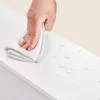 A hand is wiping a wet white surface with a cloth. Náhled obrázku produktu