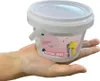A hand holding a white plastic bucket with a label on it. Produktbild-Vorschau