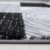 A close-up, low-angle view of a carpet with a geometric and abstract pattern. Náhled obrázku produktu