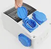 A hand is shown opening the blue cover of a white electrical distribution box with multiple blue outlets. Produktbild-Vorschau