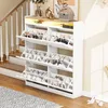 A white shoe cabinet with multiple flip-down drawers and an open shelf with LED lighting, placed next to a staircase. Náhľad obrázku produktu