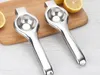 Two stainless steel lemon squeezers lie on a wooden cutting board with lemon halves. Produktbild-Vorschau