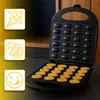 An open waffle maker with freshly made waffles, surrounded by marketing icons. Voir les images du produit