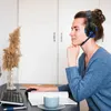 A woman wearing a headset is sitting at a desk, looking at a computer screen. Produktbild-Vorschau