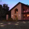 A modern house at dusk with outdoor lighting illuminating the lawn and pathway. Produktbild-Vorschau
