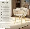 A cream-colored upholstered chair with gold legs, set in a room with a bookshelf and a cabinet. Produktbild-Vorschau