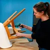 A woman is using a cordless screwdriver to fix a chair. Produktbild-Vorschau