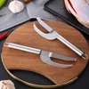 Two stainless steel fish descalers are placed on a wooden cutting board, with ingredients like garlic and chili peppers in the background. Náhled obrázku produktu