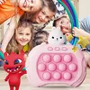 Children are playing with a pink pop-it game console with a rabbit on top, and a red monster toy. Produktbild-Vorschau