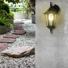 A garden path with stepping stones and gravel, leading towards a wall-mounted outdoor light fixture. Produktbild-Vorschau
