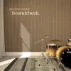 A drum set is set up in a room with a slatted wood-paneled wall and a rug on the floor. Náhled obrázku produktu