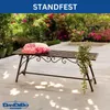 A metal garden bench with a decorative pillow and a hanging plant, set on a patio with a garden in the background. Anteprima dell’immagine prodotto