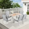 An outdoor patio set with a table and chairs on a rug, with a fence and house in the background. Produktbild-Vorschau