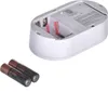 The image shows the back of a white carbon monoxide detector with its battery compartment open, and two AA batteries next to it. Podgląd zdjęcia produktu