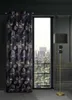 A dark, luxurious room with a large window showing a cityscape and trees. A floor lamp stands to the right of the window, and a patterned curtain hangs to the left. Produktbild-Vorschau