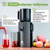 A cold press juicer is shown with juice being poured into a glass, and fruits and vegetables are arranged nearby. Podgląd zdjęcia produktu