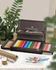 A wooden art set case with colored pencils and art supplies is open on a table, with art paper and rolls of paper in the foreground. Anteprima dell’immagine prodotto